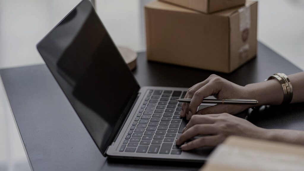 ノートPCでECの受注を確認する手元と段ボール