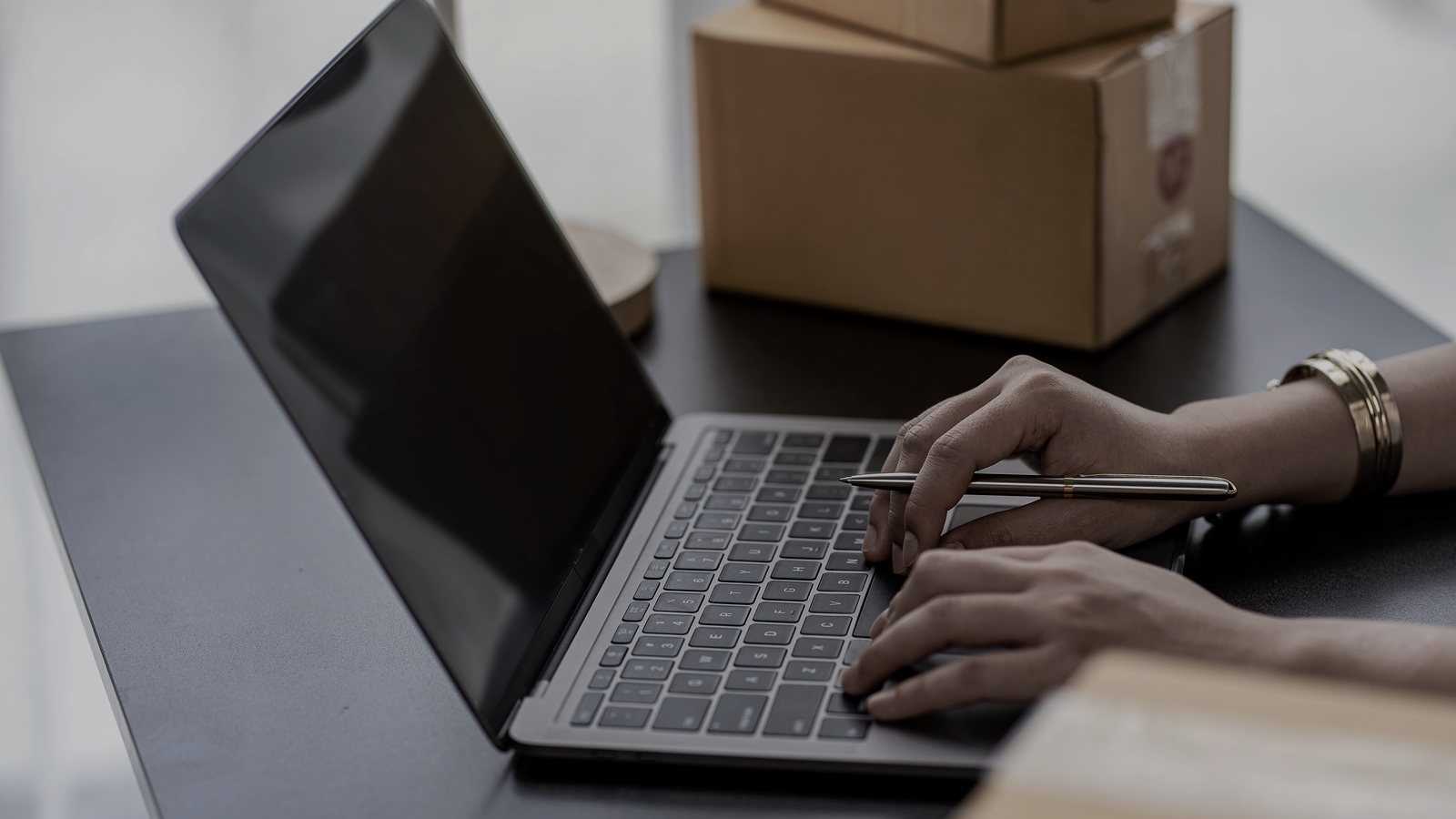 ノートPCでECの受注を確認する手元と段ボール